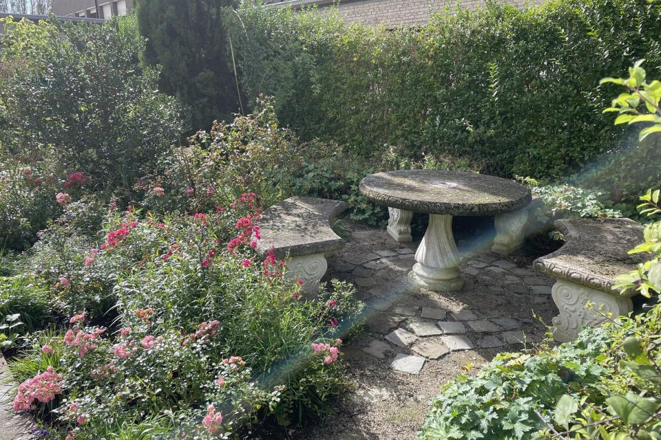 Rozentuin met zitplek in de 'Romeinse Tuin'. Vloer van puin en brekerzand.